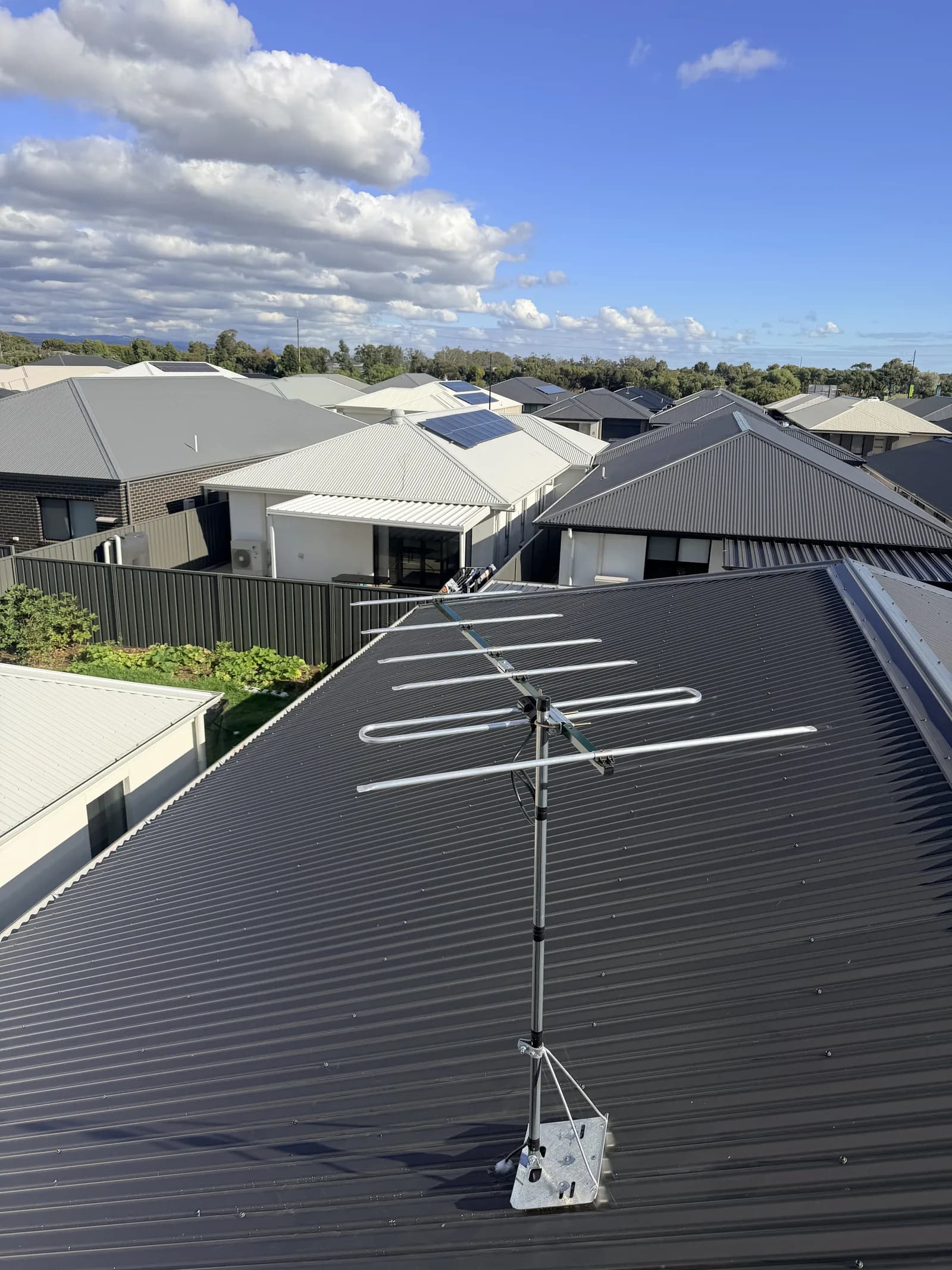A TV antenna installed on an Adelaide rooftop with the suburb behind